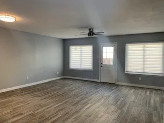 an empty room with wooden floor and windows