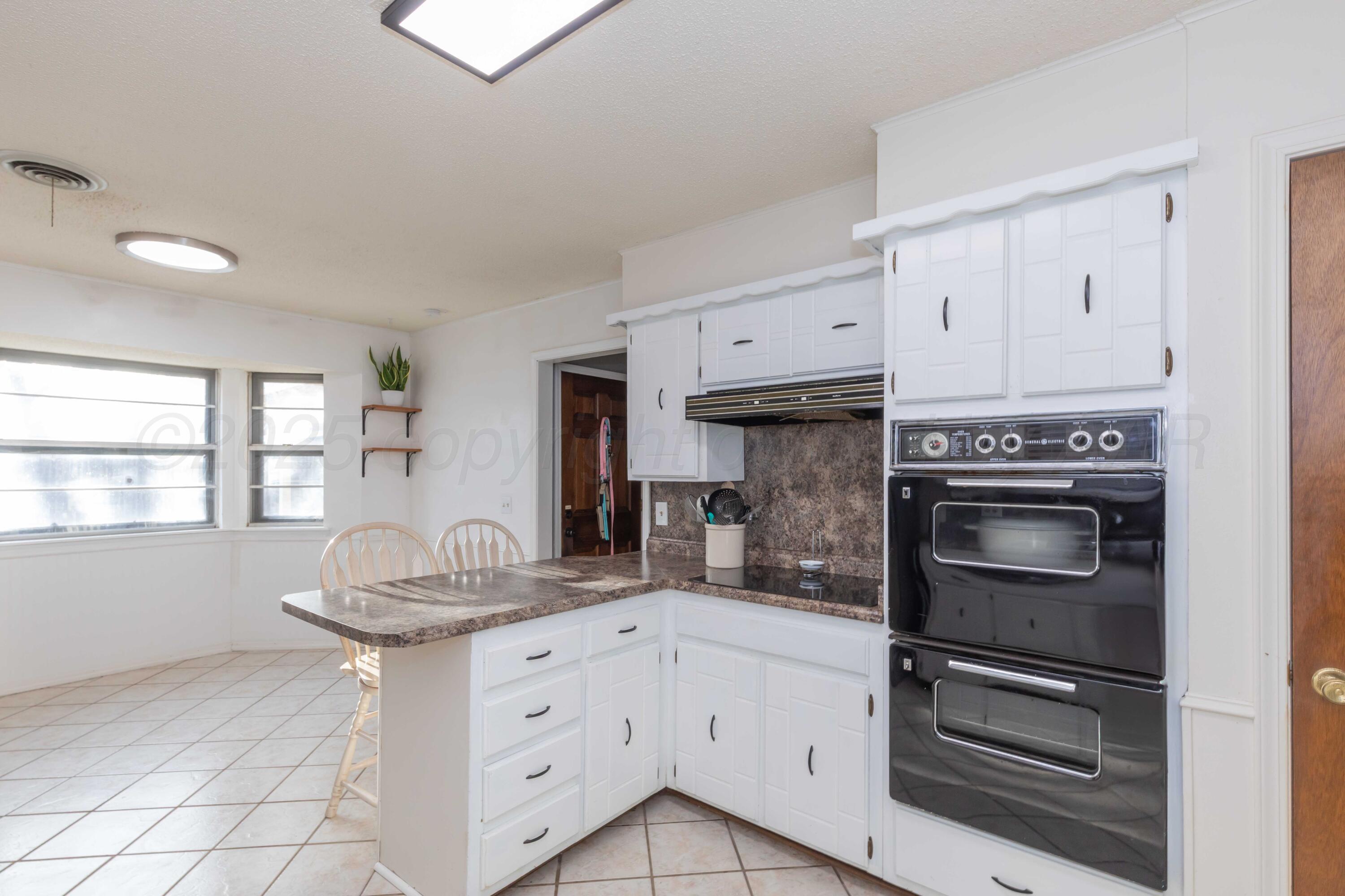 5301 Leigh Avenue Amarillo, TX 79110 - Photo 13 of 35 a kitchen with granite countertop a stove cabinets and window