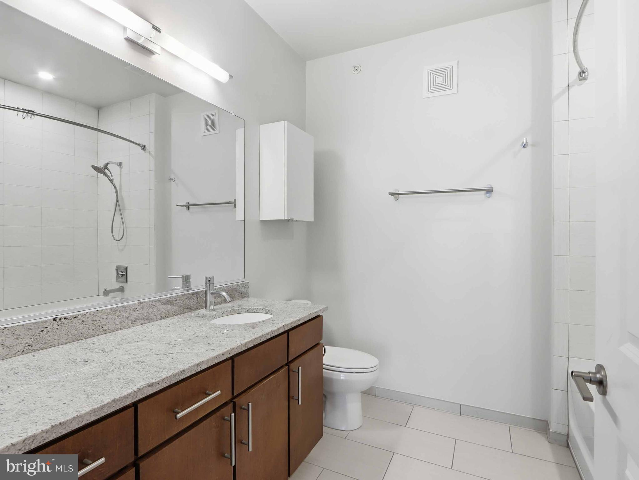 8005 13th Street, Unit 411 Silver Spring, MD 20910 - Photo 30 of 33 a bathroom with a granite countertop sink toilet and shower