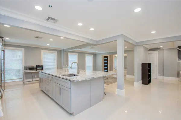 a large white kitchen with a sink dishwasher a stove and a refrigerator with wooden floor