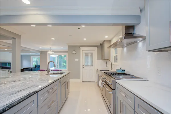 a large kitchen with a large counter top space a sink stainless steel appliances and cabinets