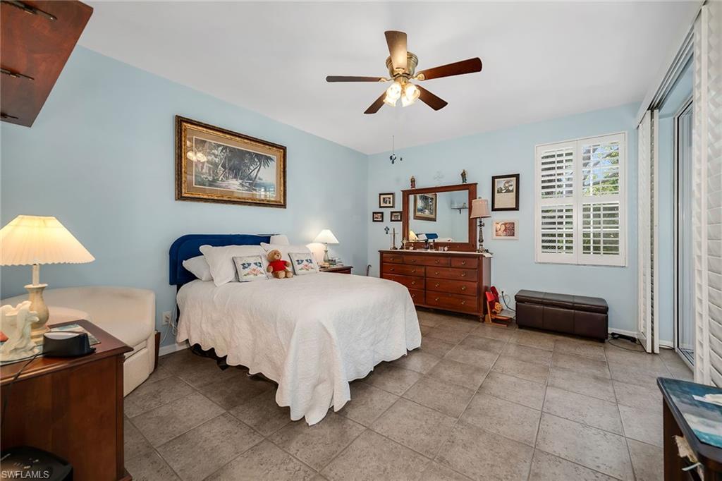 3755 Fieldstone Boulevard, Unit 1203 Naples, FL 34109 - Photo 15 of 50 a bedroom with a bed and a chandelier