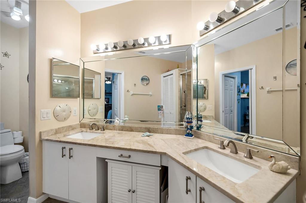 3755 Fieldstone Boulevard, Unit 1203 Naples, FL 34109 - Photo 19 of 50 a bathroom with a granite countertop sink a large mirror and a toilet