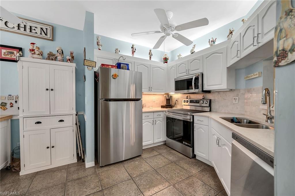 3755 Fieldstone Boulevard, Unit 1203 Naples, FL 34109 - Photo 3 of 50 a kitchen with stainless steel appliances granite countertop a refrigerator a oven a sink a stove and white cabinets