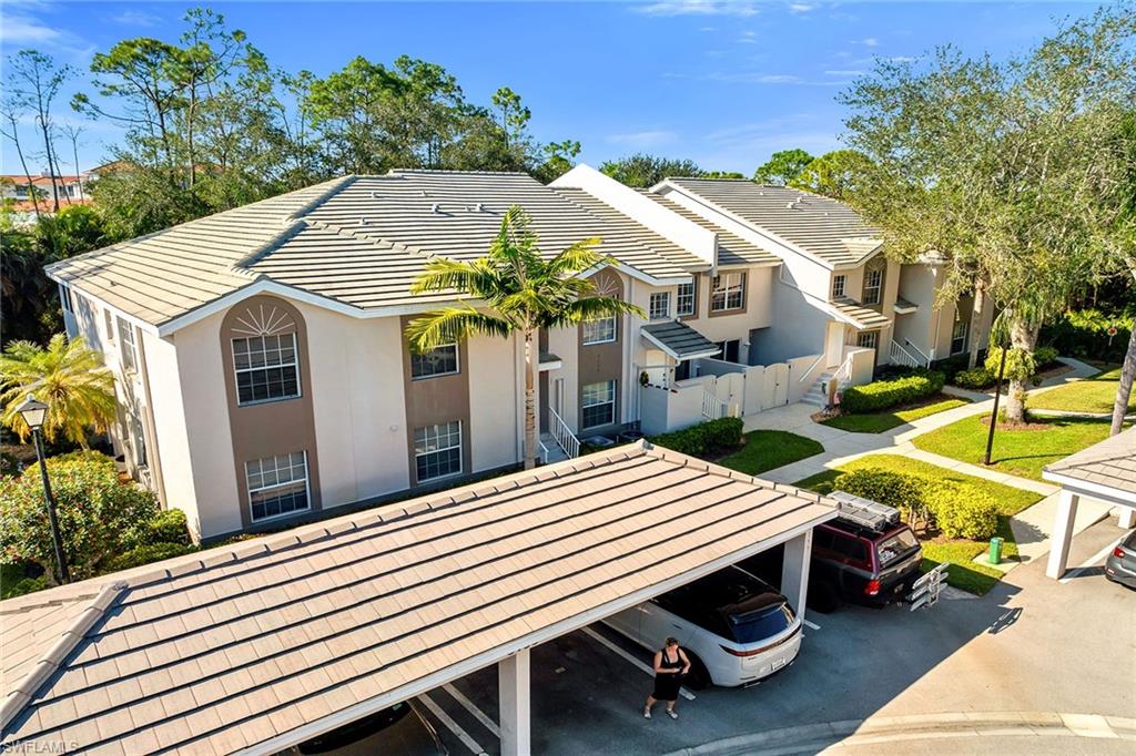 3755 Fieldstone Boulevard, Unit 1203 Naples, FL 34109 - Photo 45 of 50 a backyard of a house with table and chairs under an umbrella