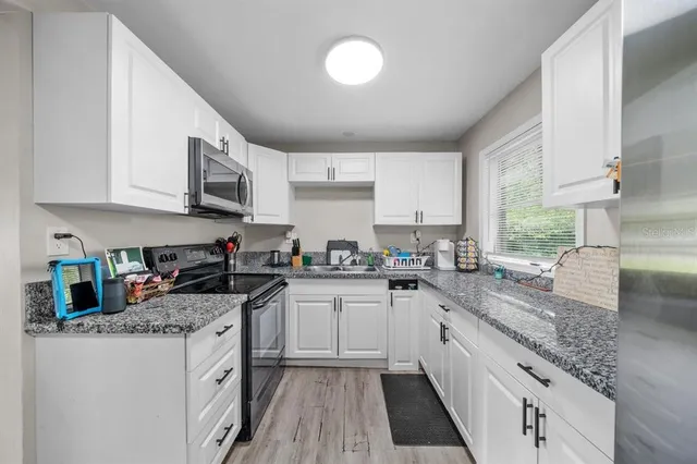a kitchen with stainless steel appliances granite countertop a sink stove and cabinets
