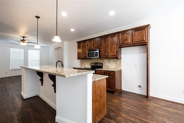 a kitchen with stainless steel appliances granite countertop a refrigerator a stove a sink and dishwasher with wooden cabinets