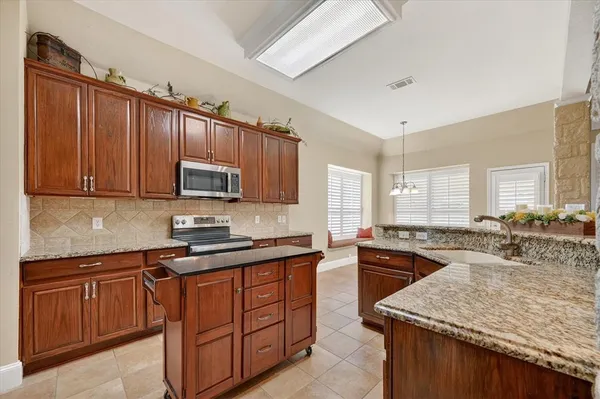 a kitchen with stainless steel appliances granite countertop a sink stove and refrigerator