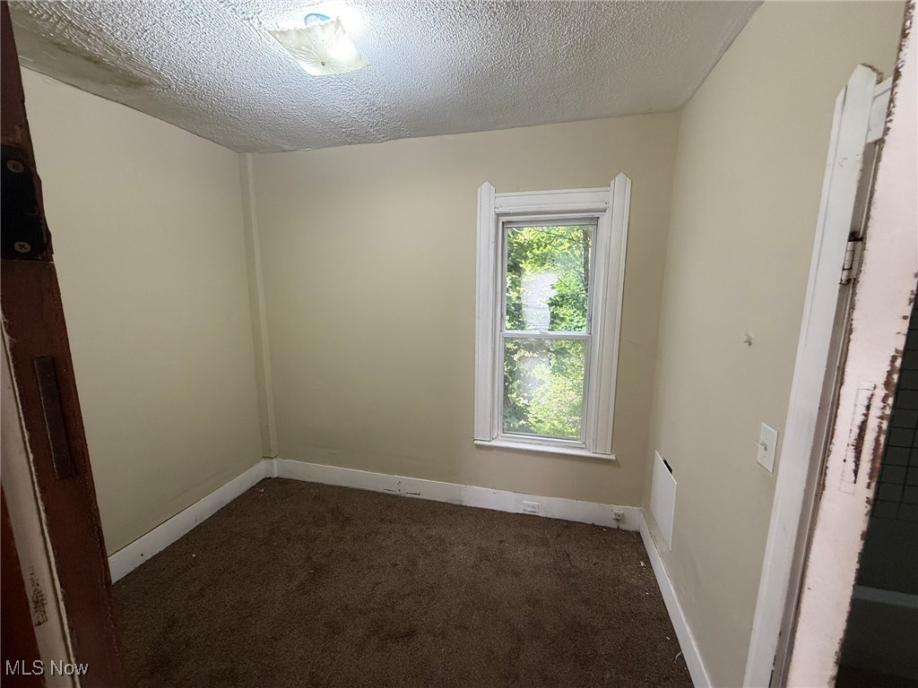 1355 Addison Road Cleveland, OH 44103 - Photo 7 of 23 Spare room with dark colored carpet and a textured ceiling