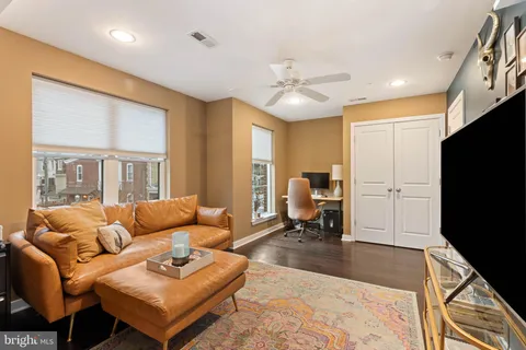 a living room with furniture two window and a flat screen tv