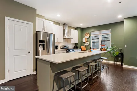 a kitchen with stainless steel appliances a sink a stove a refrigerator with wooden floor