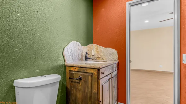 a bathroom with a granite countertop sink a toilet and a mirror
