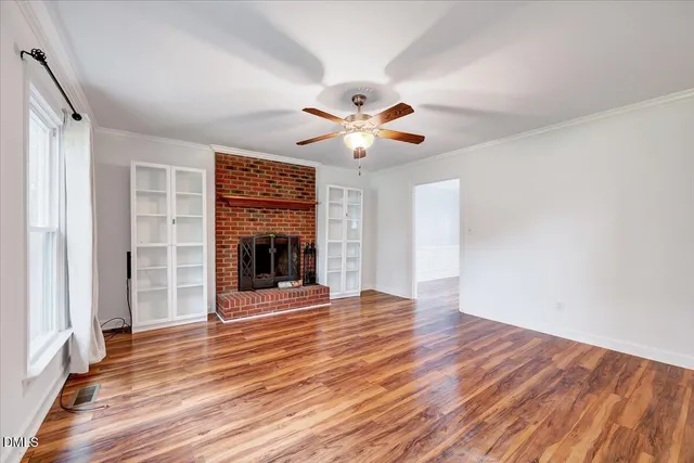a view of an empty room with a window and wooden floor