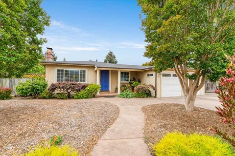 a front view of a house with a yard and potted plants