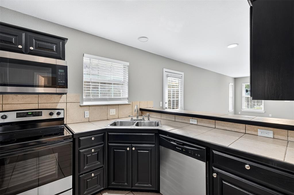 1021 Rice Street, Unit 101 Denison, TX 75020 - Photo 9 of 22 a kitchen with granite countertop a sink stainless steel appliances and cabinets