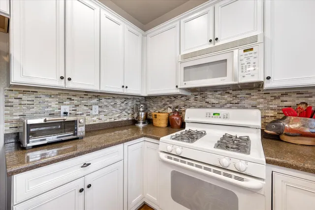 a kitchen with granite countertop cabinets and white appliances