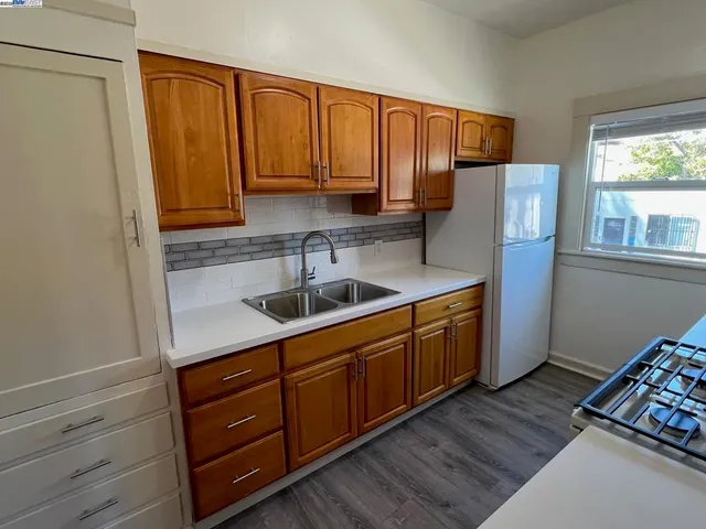 a kitchen with stainless steel appliances granite countertop a refrigerator a sink dishwasher and wooden cabinets with wooden floor