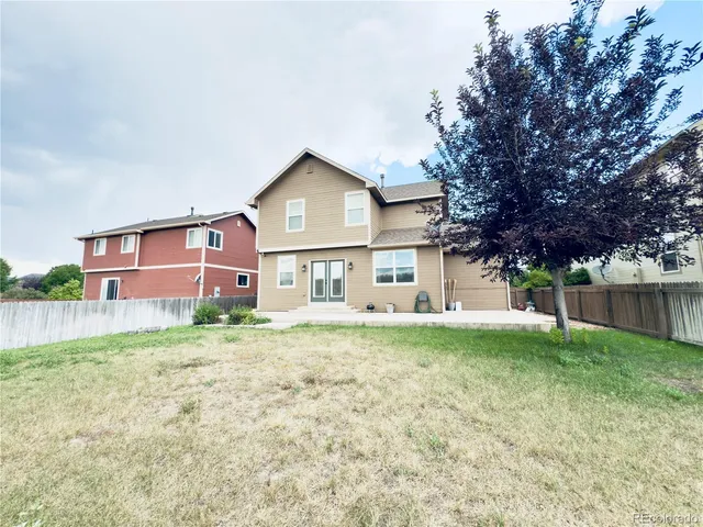 a view of a yard in front of a house with large tree