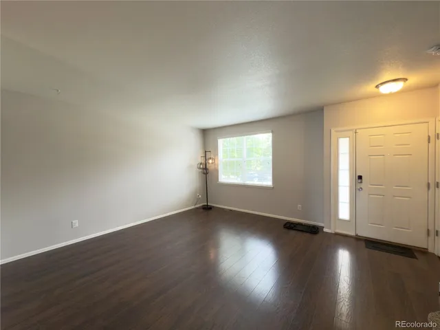 an empty room with wooden floor and windows with curtains