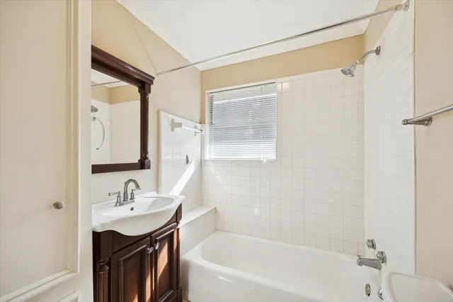 a bathroom with a bathtub shower sink vanity and mirror