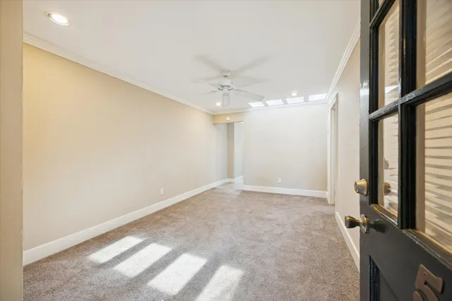 an empty room with a chandelier fan and windows