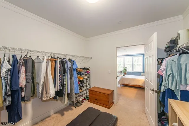 a walk in closet with clothes and shoes