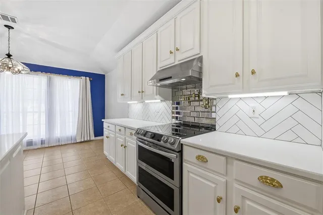 a kitchen with stainless steel appliances a stove a white cabinet and a white cabinets