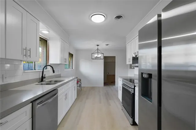 a kitchen with stainless steel appliances granite countertop a sink refrigerator and cabinets