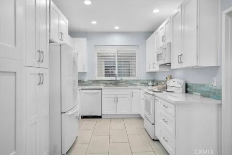 a kitchen with granite countertop white cabinets and white appliances