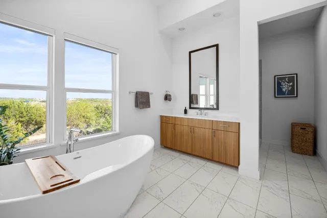 a bathroom with a tub a double vanity sink a mirror and a bathtub