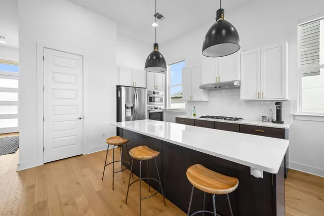 a kitchen with stainless steel appliances granite countertop a sink a stove and chairs in it