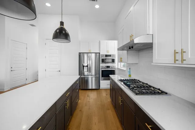 a kitchen with stainless steel appliances a sink a stove a refrigerator cabinets and wooden floor