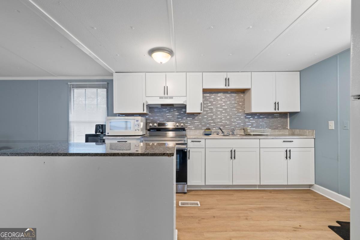 158 Thomas Field Road Southeast Milledgeville, GA 31061 - Photo 11 of 28 a kitchen with granite countertop a sink cabinets and wooden floor