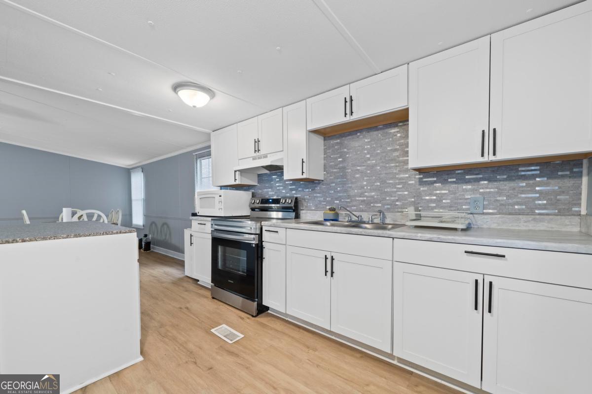 158 Thomas Field Road Southeast Milledgeville, GA 31061 - Photo 12 of 28 a kitchen with granite countertop white cabinets and white appliances