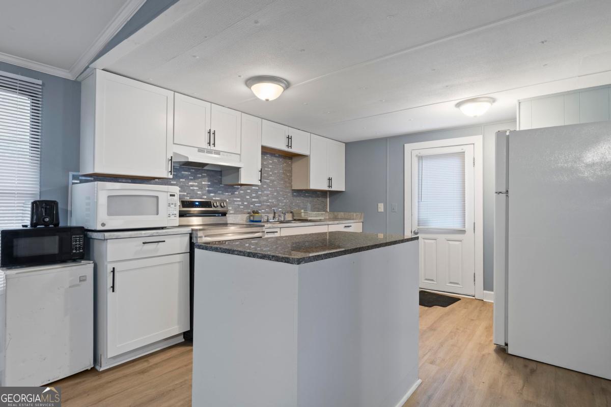158 Thomas Field Road Southeast Milledgeville, GA 31061 - Photo 9 of 28 a kitchen with a sink a stove a refrigerator and white cabinets