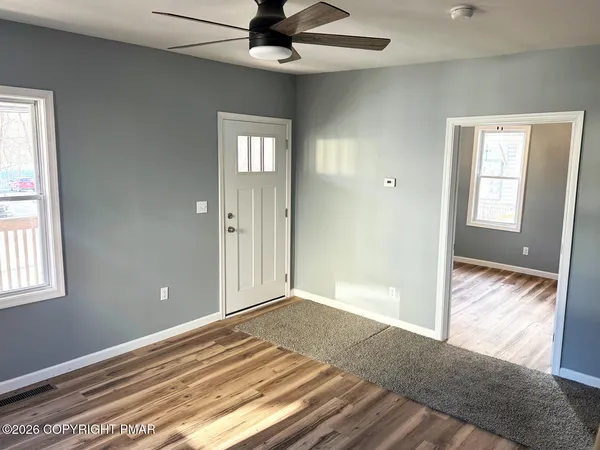 a view of an empty room with wooden floor and a window