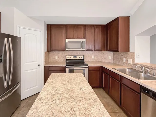 a kitchen with a refrigerator sink and wooden cabinets