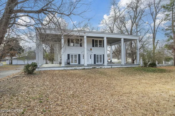 front view of a house with a yard and an trees