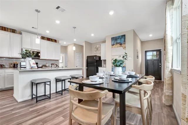 a kitchen with a dining table chairs wooden floor appliances and cabinets