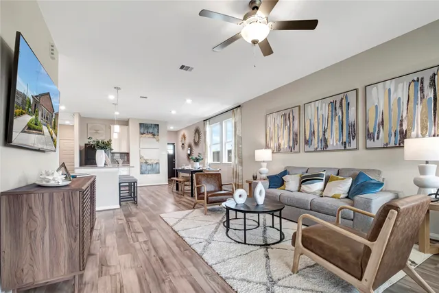 a living room with furniture kitchen view and a wooden floor