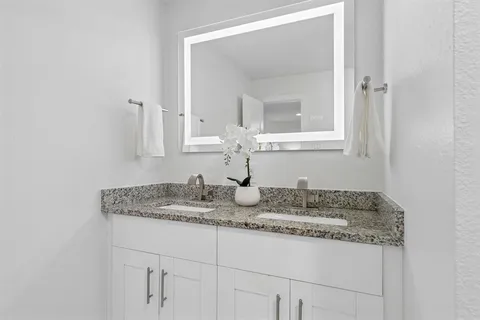 a bathroom with a granite countertop sink and a mirror