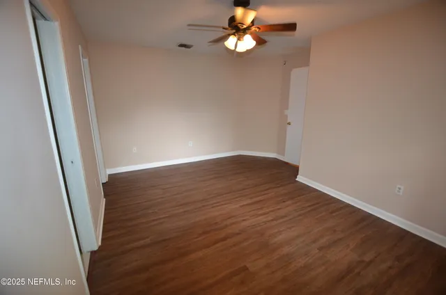 an empty room with wooden floor and fan