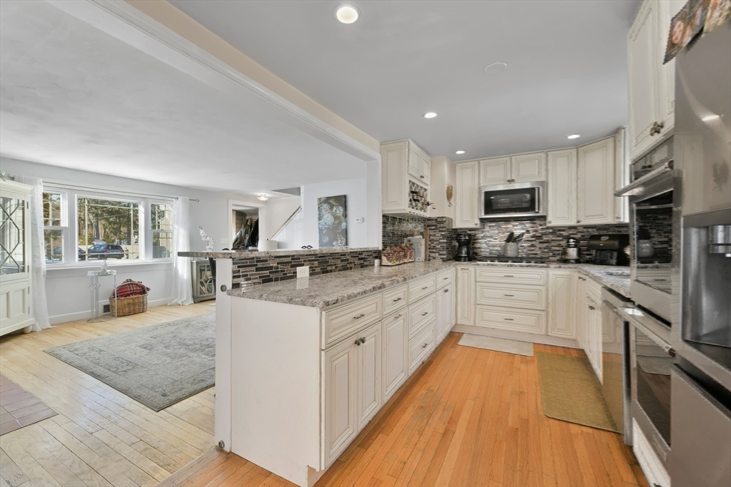 22 Stratford Road Natick, MA 01760 - Photo 14 of 41 a kitchen with stainless steel appliances granite countertop a stove top oven a sink dishwasher and a refrigerator with wooden floor