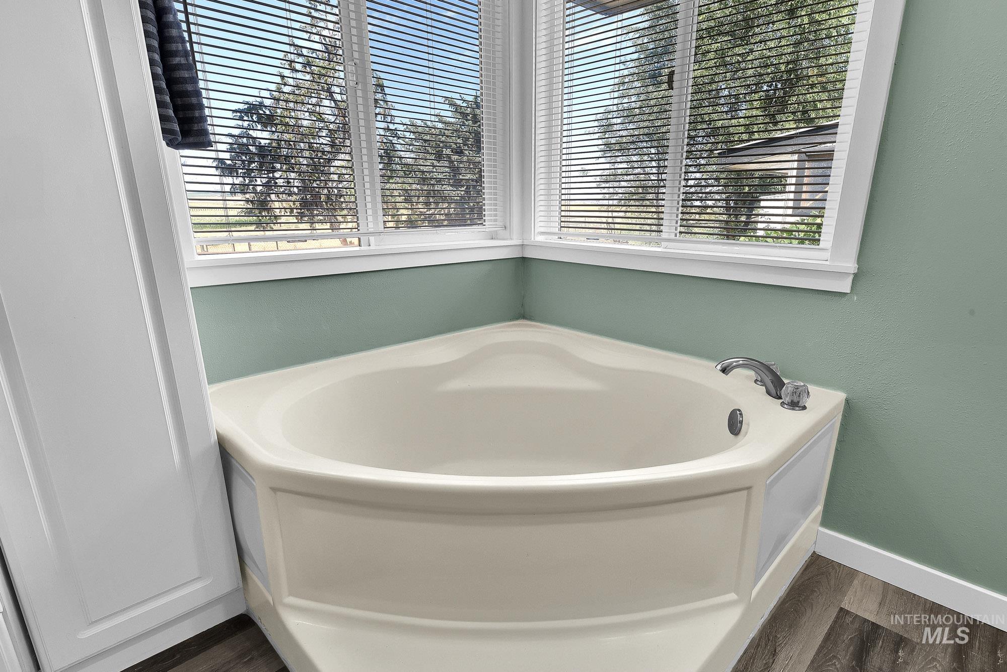 5755 Chuckwagon Road Nampa, ID 83686 - Photo 23 of 50 Corner soaking tub with chrome fixtures, wood-finish flooring, and natural light from horizontal blinds