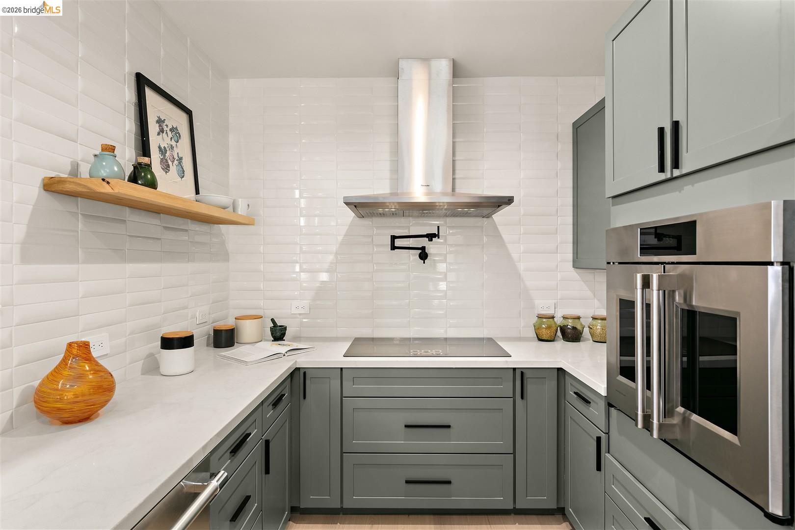 1668 Arch Street Berkeley, CA 94709 - Photo 19 of 78 U-shaped kitchen featuring grey cabinetry, white countertops, built-in stainless steel double ovens, a stainless steel range hood, and white textured tile backsplash