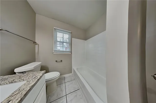 a bathroom with a granite countertop toilet a sink and bathtub
