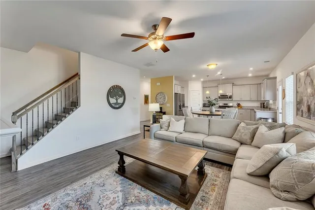 a living room with white couches and a dining table with wooden floor