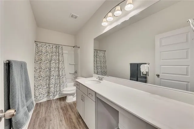 a bathroom with a sink a toilet a mirror and shower