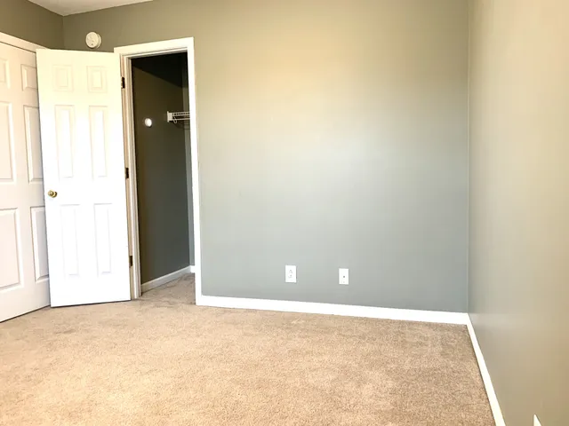 a view of an empty room with closet and a window