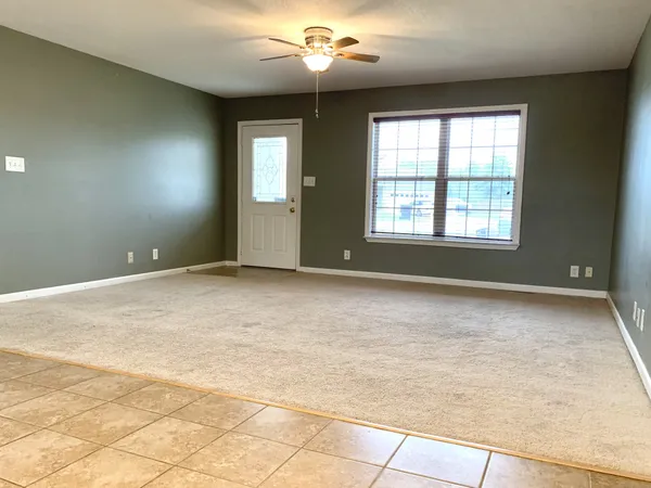 a view of an empty room with window and chandelier fan
